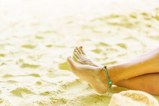 Woman feet leg near beach sand red nails 