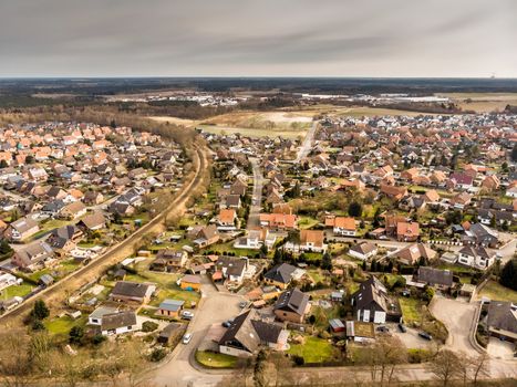 Aerial photos of a village in Germany crossed by a single-track railway line with grey sky in the background, made with drone
