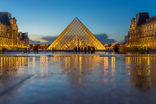 PARIS, FRANCE - DECEMBER 08, 2017: View of famous Louvre Museum with Louvre Pyramid at evening. Louvre Museum is one of the largest and most visited museums worldwide