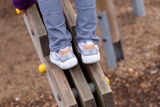 A young boy on a wooden climbing frame in Battersea Park, London