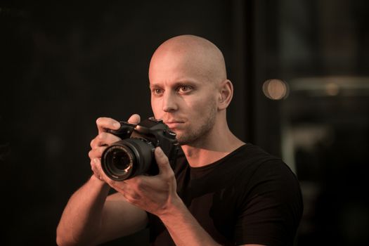 photographer at work holding camera shaved head white man equipment.