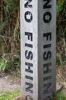 A vertical no fishing warning on a concrete post