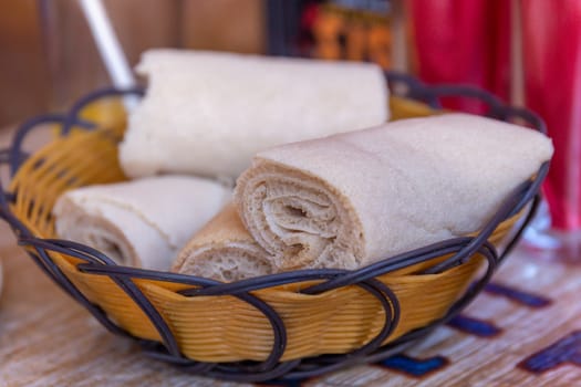Rolls of Injera in a serving bowl.  Injera is a sourdough flatbread made from teff flour.  It is the national dish of Ethiopia, Eritrea, Somalia and Djibouti