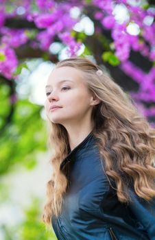 Romantic young girl with blooming lilac in the background