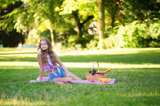 Pretty young girl having a picnic in park