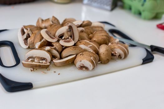 A pile of sliced chestnut mushrooms (Agaricus bisporus) on a white chopping board