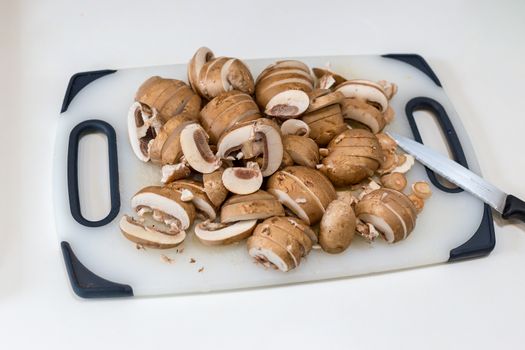 A pile of sliced chestnut mushrooms (Agaricus bisporus) on a white chopping board