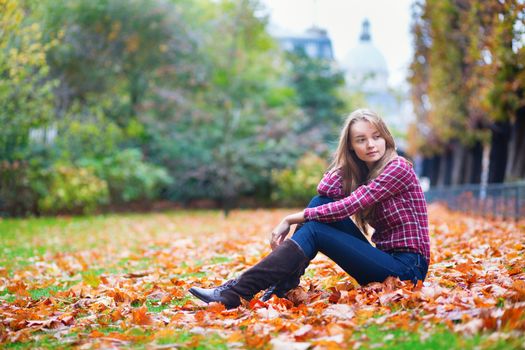 Thoughtful young girl sitting on the ground at fall