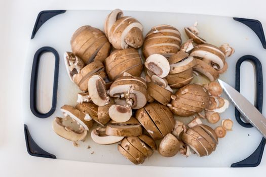 A pile of sliced chestnut mushrooms (Agaricus bisporus) on a white chopping board