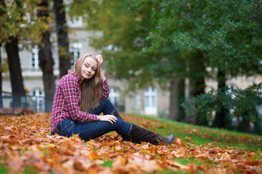 Thoughtful girl sitting on the ground at fall