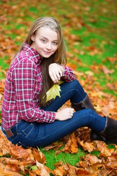 Beautiful girl sitting on the ground in fall park