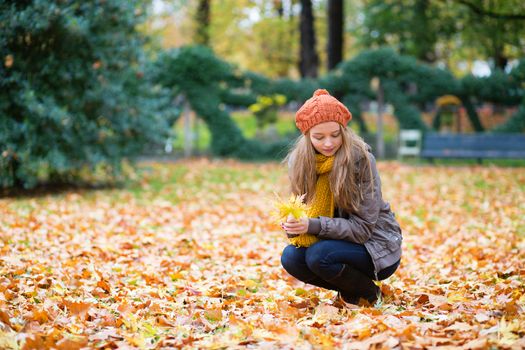 Girl gathering autumn leaves in a park