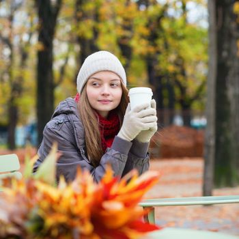 Girl drinking coffee or tea outdoors on a fall day