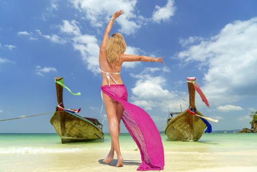 Woman on Tropical beach relaxing and watching longtail boats, Andaman Sea, Thailand