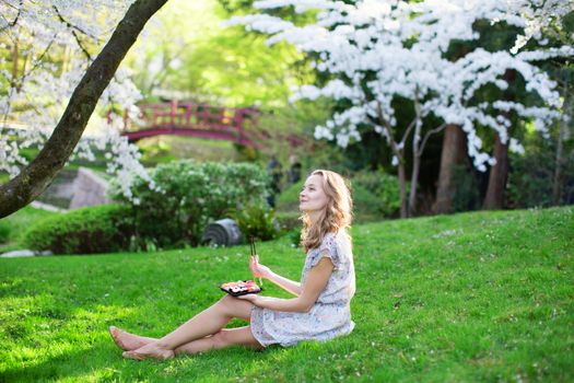 Young woman eating sushi in Japanese park.