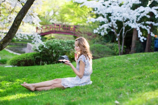 Young woman eating sushi in Japanese park.