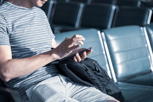 Man using a smartphone in the departure lounge of an airport