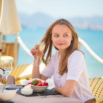 Beautiful young woman eating fruits in a beach restaurant