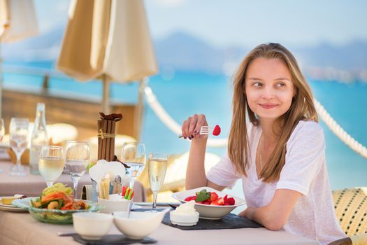 Beautiful young woman eating fruits in a beach restaurant