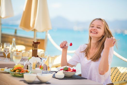 Beautiful young woman eating fruits in a beach restaurant