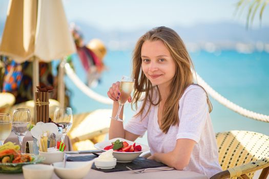 Beautiful young woman eating fruits in a beach restaurant