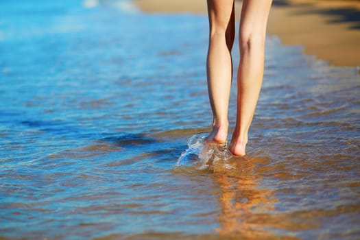 Closeup of legs of a woman walking on the beach