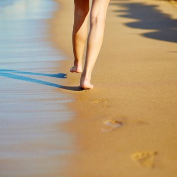 Closeup of legs of a woman walking on the beach