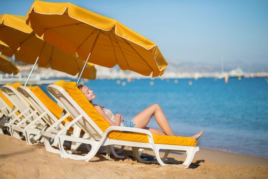 Beautiful girl relaxing on a beach chair near the sea