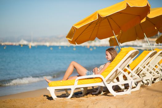 Beautiful girl relaxing on a beach chair near the sea