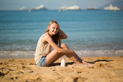 Beautiful young woman applying sunscreen on her legs 