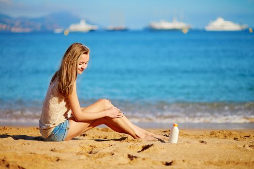 Beautiful young woman applying sunscreen on her legs