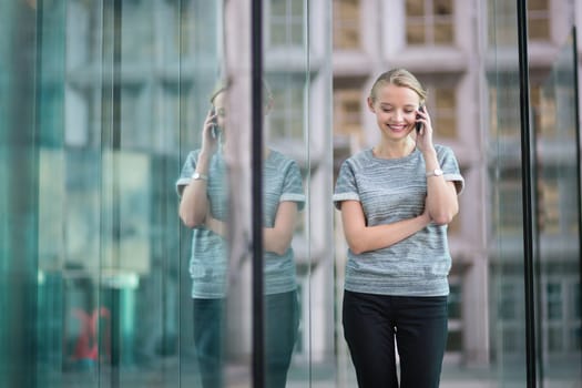 Young beautiful business woman in modern glass interior speaking on the phone
