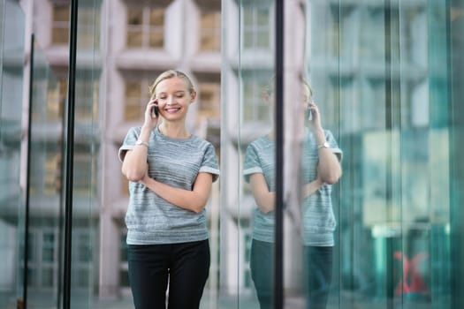 Young beautiful business woman in modern glass interior speaking on the phone