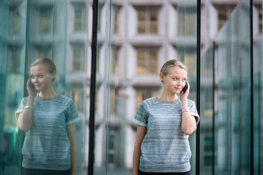 Young beautiful business woman in modern glass interior speaking on the phone