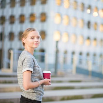 Young beautiful woman having her coffee break outside of the office or university 