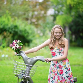 Beautiful young girl with bicycle in the countryside