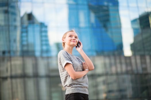Young beautiful business woman in modern glass interior speaking on the phone