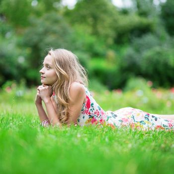 Beautiful young girl lying on the grass and enjoying summer day