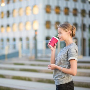 Young beautiful woman having her coffee break outside of the office or university