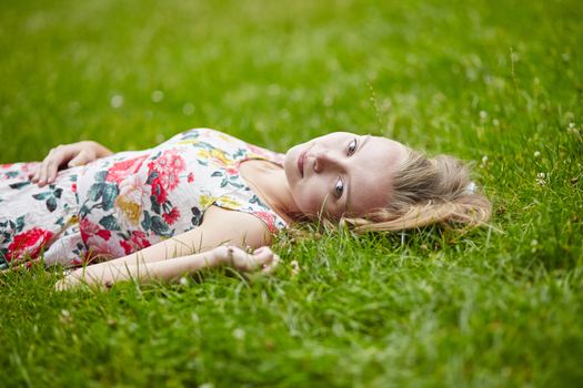 Beautiful young girl lying on the grass on a summer day 
