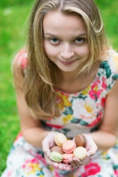 Beautiful young girl holding traditional French macaroons in hands