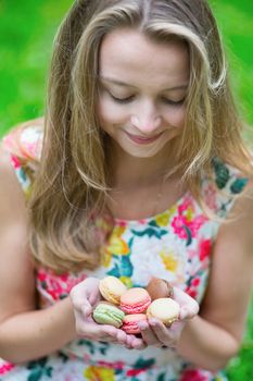 Beautiful young girl holding traditional French macaroons in hands