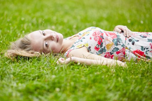 Beautiful young girl lying on the grass on a summer day 