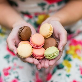 Girl holding colorful French macaroons in hands