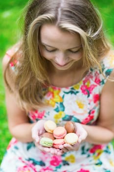 Beautiful young girl holding traditional French macaroons in hands