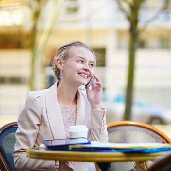 Young businesswoman on a coffee break, working and speaking on the phone