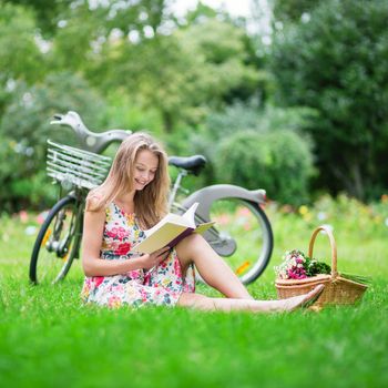 Beautiful young girl reading in a park