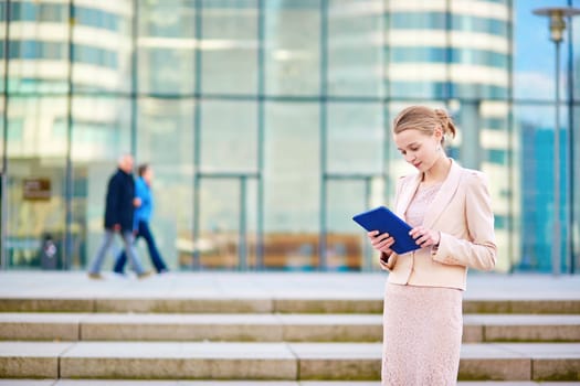 Young beautiful business woman in modern glass interior using tablet