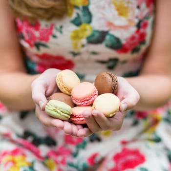 Closeup of female hands holding colorful French macaroons