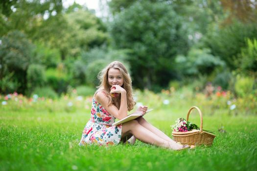 Beautiful young girl with bicycle in the countryside, reading a book